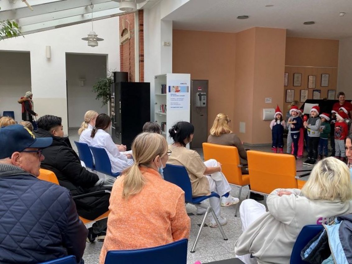 Viele Menschen sitzen im Foyer des Krankenhauses und schauen dem Kinderchor zu